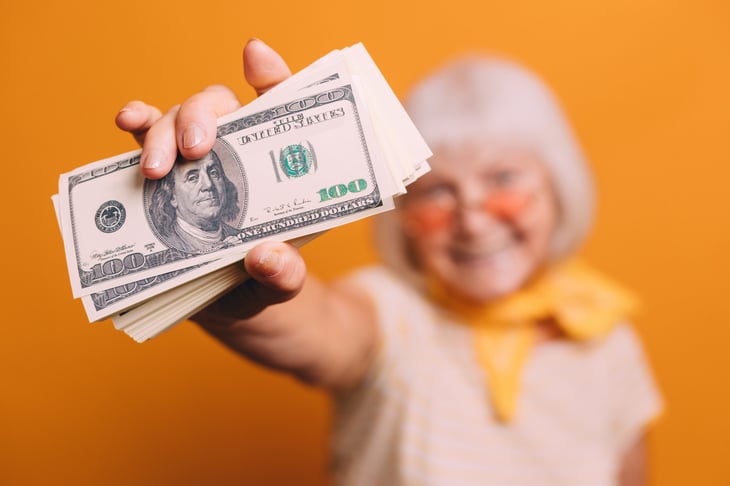 Retiree holding stack of $100 bills