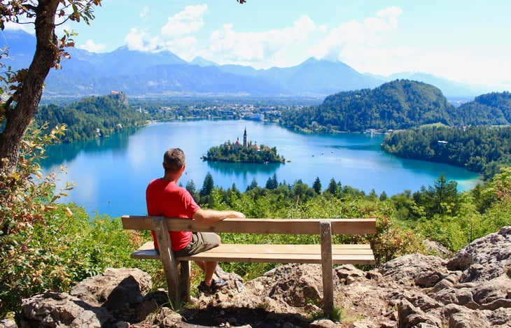 Man celebrating early retirement overlooking a lake and mountains in nature