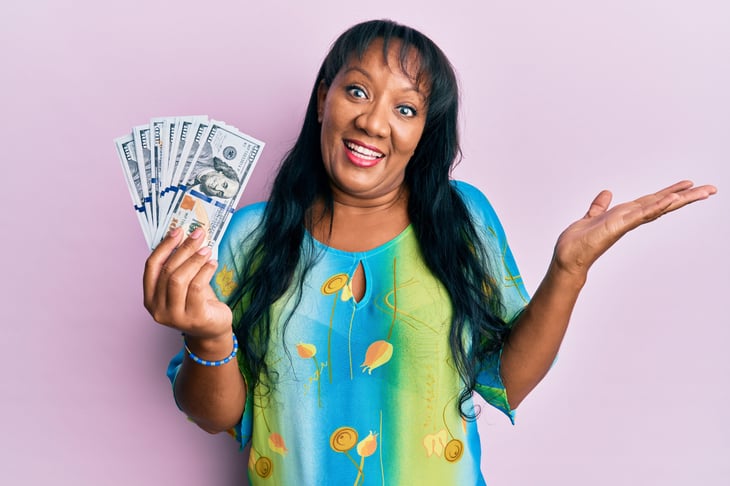 Middle-aged woman smiling and holding money