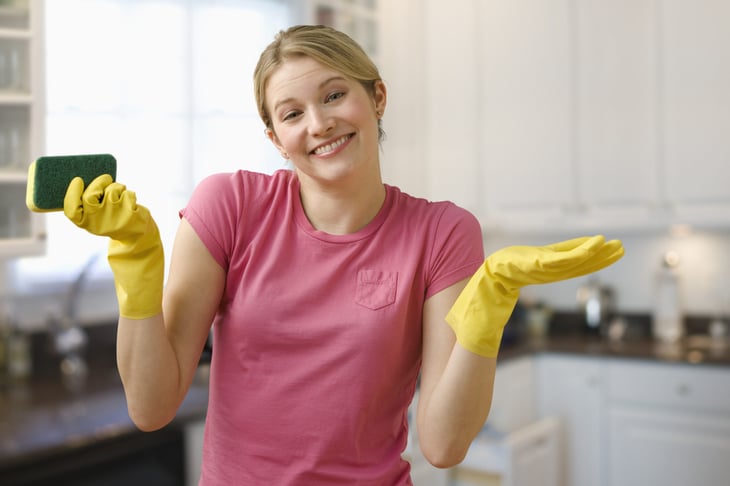 woman with cleaning gloves and sponge in kitchen