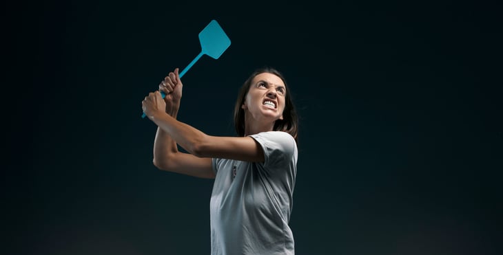 Woman with fly swatter trying to kill bugs or mosquitoes