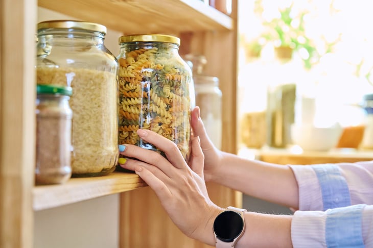 Woman taking jar of dried pasta off shelf