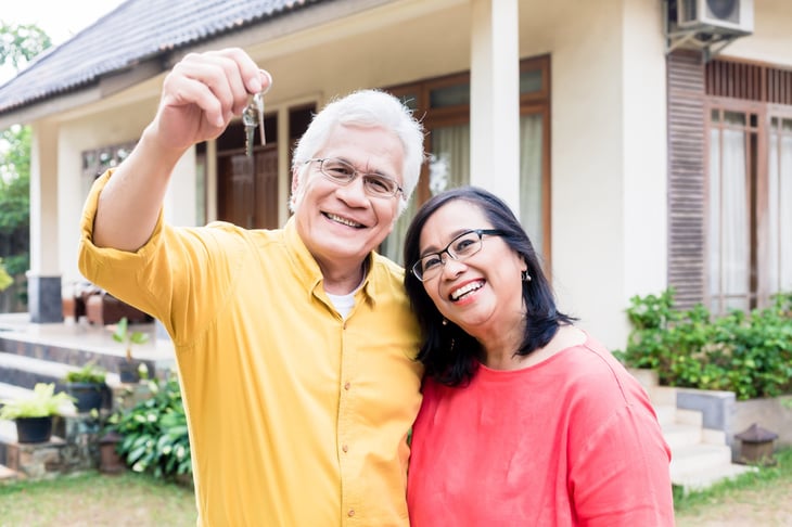 Happy older couple in front of a home they bought or sold