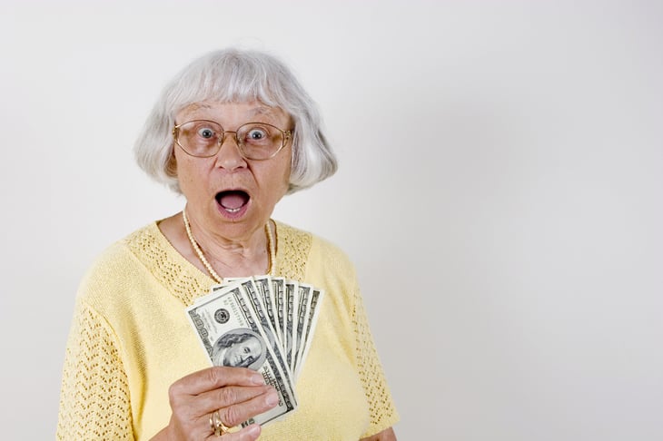 surprised senior with cash
