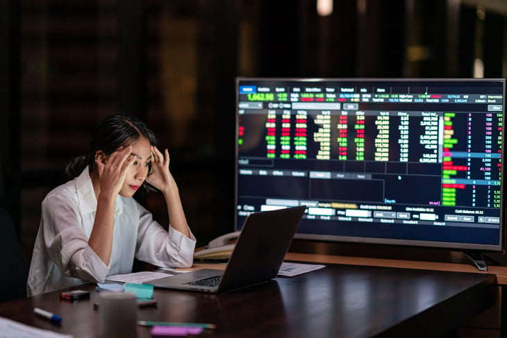 Stressed woman looking at stock drops and making investing decisions