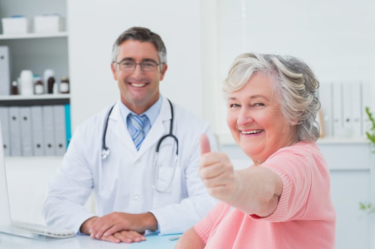Senior woman gives thumbs up to doctor