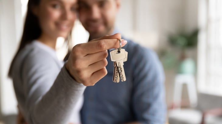Couple with keys to a house or apartment after signing a lease or purchasing a home