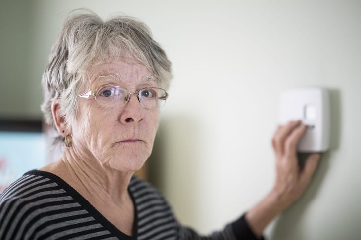 Older woman adjusting her thermostat