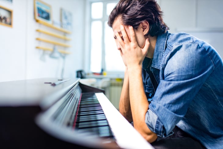 man frustrated unhappy over piano