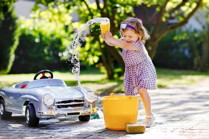 girl playing with water and sponge outside