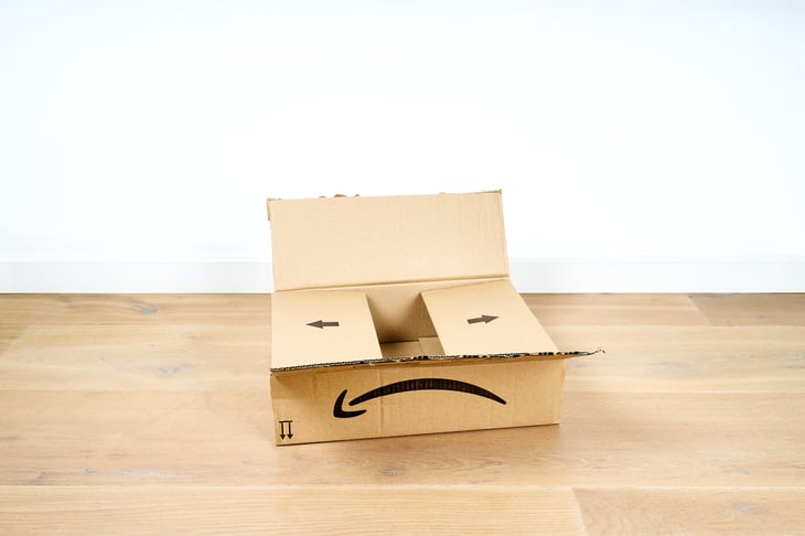 Sad empty Amazon box with a frowny face; an empty package delivered in an empty room
