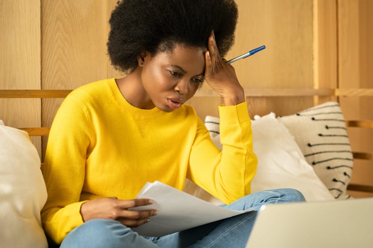 Upset woman reading documents on her sofa
