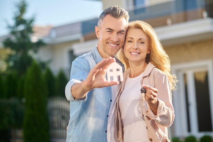 Wealthy couple in front of their new house