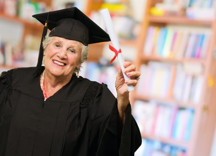 Senior college graduate holding degree or diploma wearing a graduation cap and gown