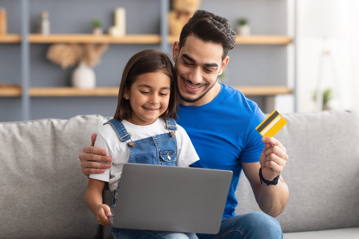 Father and daughter using a credit card to do school shopping on a laptop