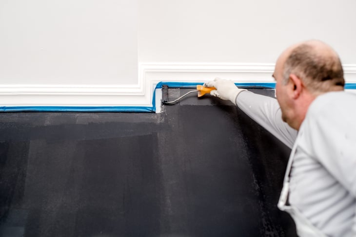 Man painting a dark gray wall