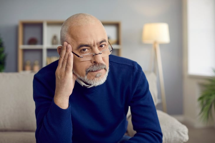 Skeptical senior looks worried or has a headache