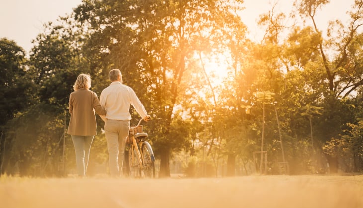 Happy senior couple biking outdoors at sunset
