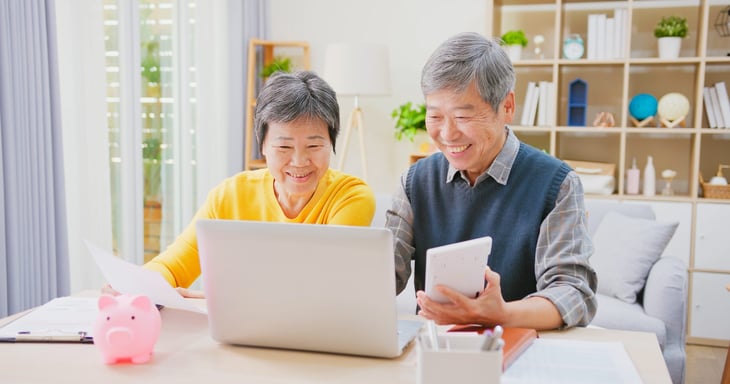 Happy senior couple saving money and budgeting or doing math for retirement income