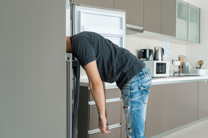 Man looking in fridge with head stuck in freezer