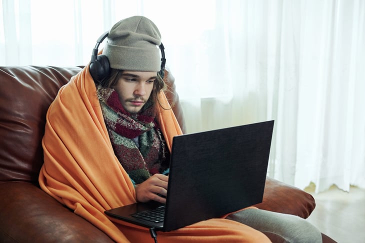 Man on laptop using a heated blanket to keep warm