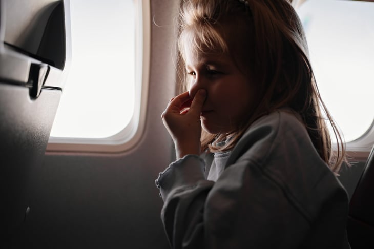 Girl holding her nose because of a bad smell on the plane