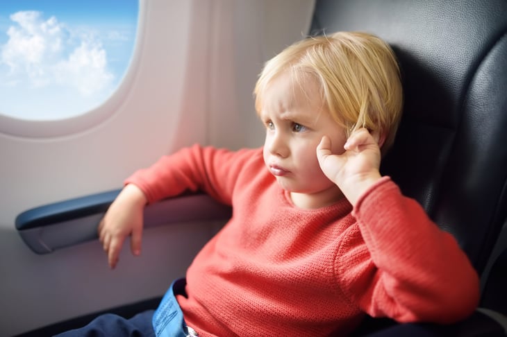 Angry, grumpy or annoyed child on a plane