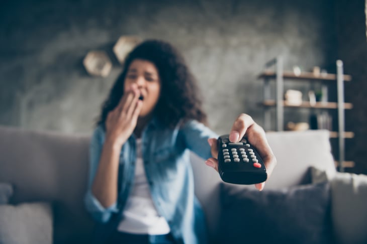 Yawning bored woman turning off TV