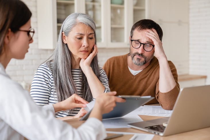 Worried couple talking to financial adviser about savings and retirement planning and debt