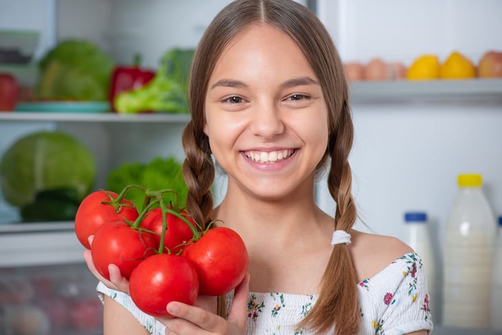Girl with tomatoes in front of fridge