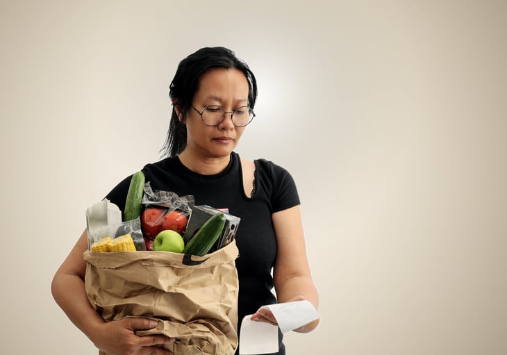 Woman with groceries looking at savings