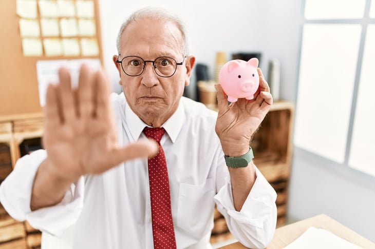 Upset senior man with a piggy bank
