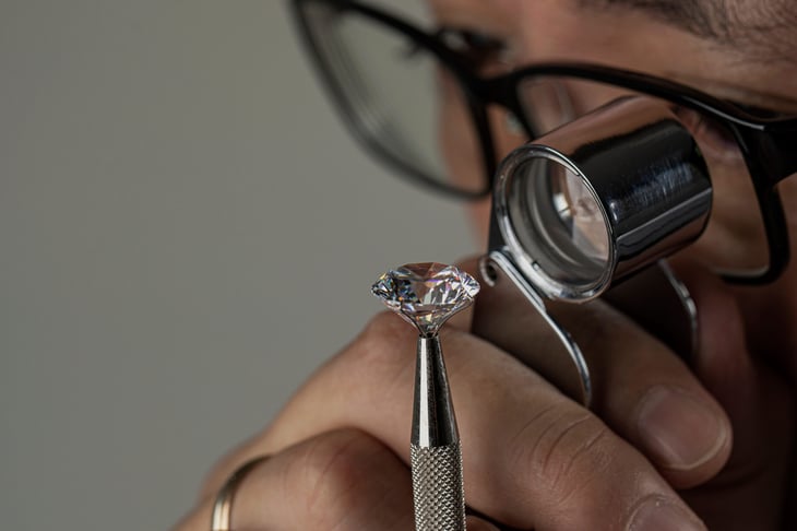 Jeweler man examining diamond close up with jeweler's loupe