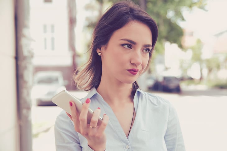Annoyed woman looking away from her smartphone outdoors