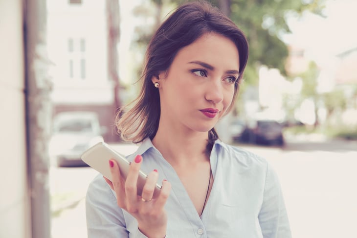 Annoyed woman looking away from her smartphone outdoors