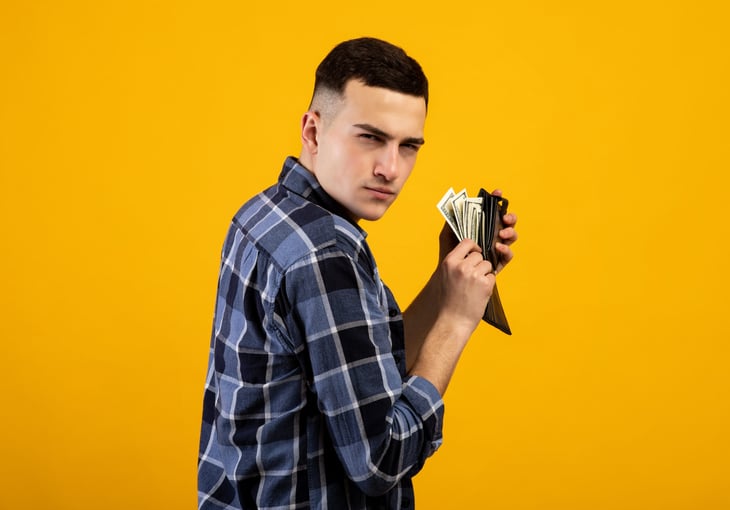 stingy man putting money in wallet