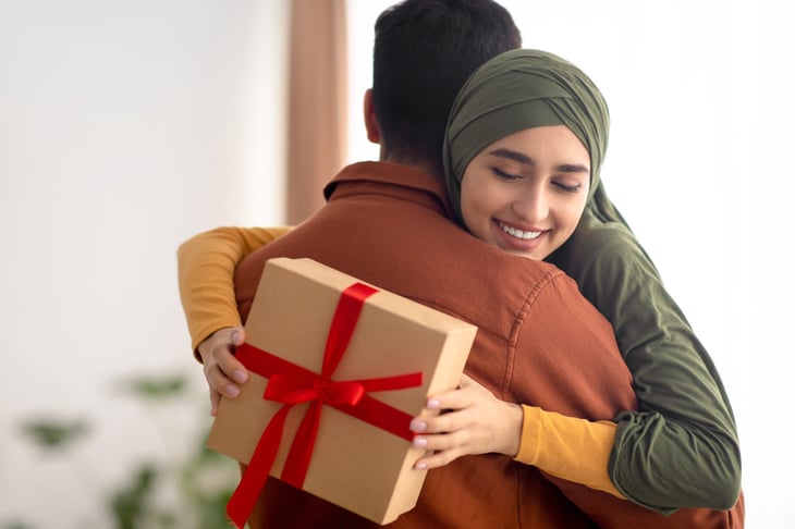 Couple hugging while exchanging holiday gifts