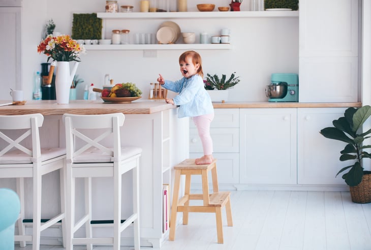 Little girl standing on stepstool in kitchen
