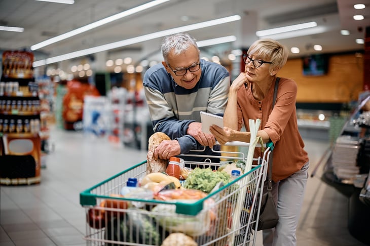 Happy senior couple shopping for food and groceries with a shopping cart in the grocery store