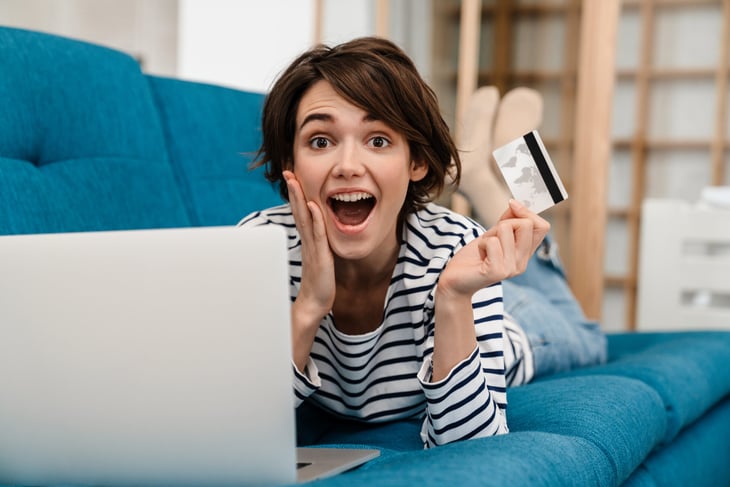 Woman excited about her credit card rewards and using a laptop to book travel