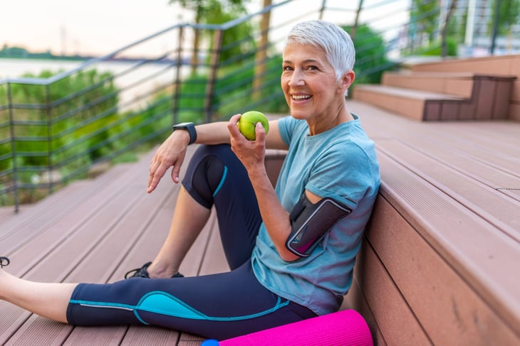 Healthy active senior woman eating an apple