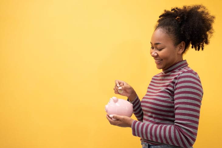 Woman putting money in piggy bank