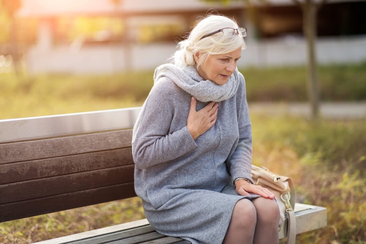 Older woman on a park bench suffering heart pain or difficulty breathing
