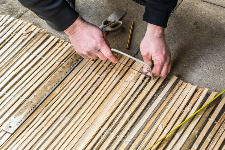 A man cuts bamboo screening