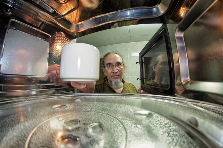 Man putting a mug in a microwave