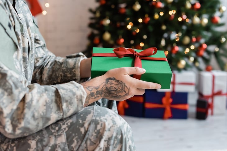 Military member holding a Christmas gift