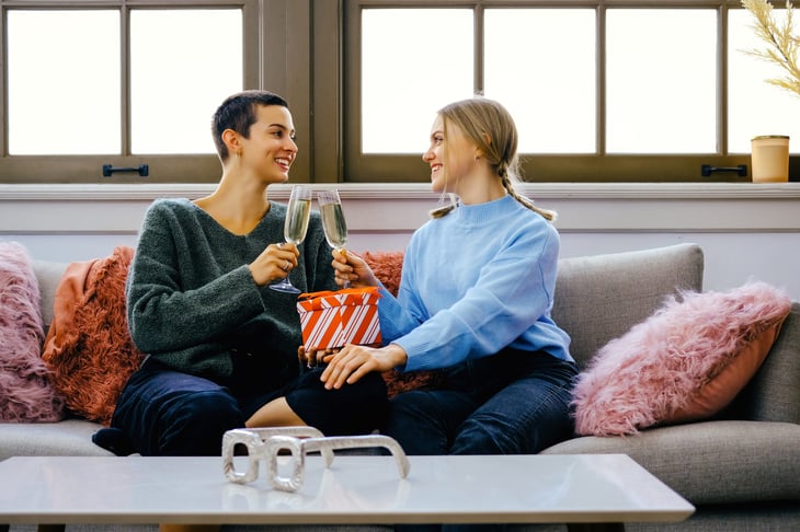 Couple exchanging holiday gifts and drinking champagne 