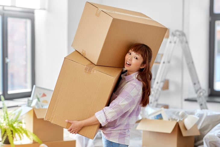 Excited woman carrying moving boxes to her new home