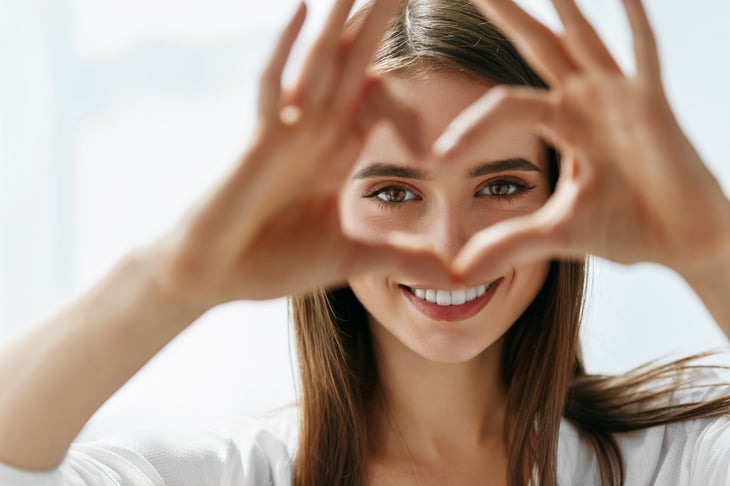 Woman making heart with fingers around eyes