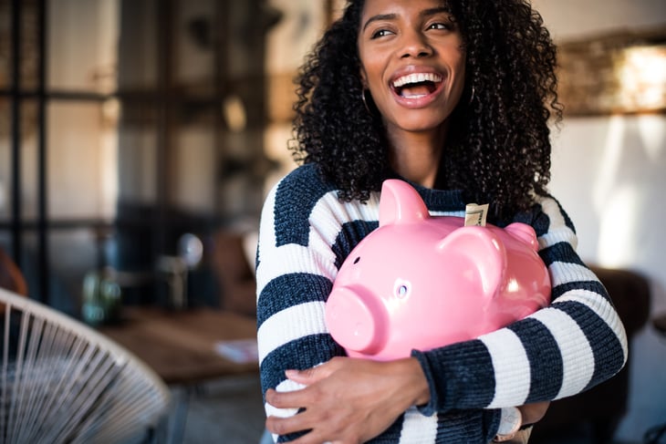 Happy woman hugging a large piggy bank